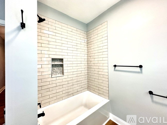 A bathroom with a white tub and a brick wall.