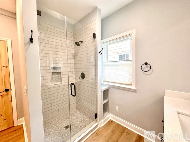 A bathroom with a walk-in shower and a window.