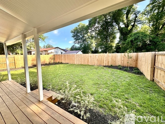 A backyard with a wooden deck and a fence.