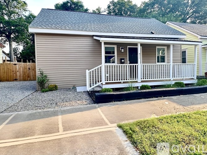 A small house with a porch and a fence.