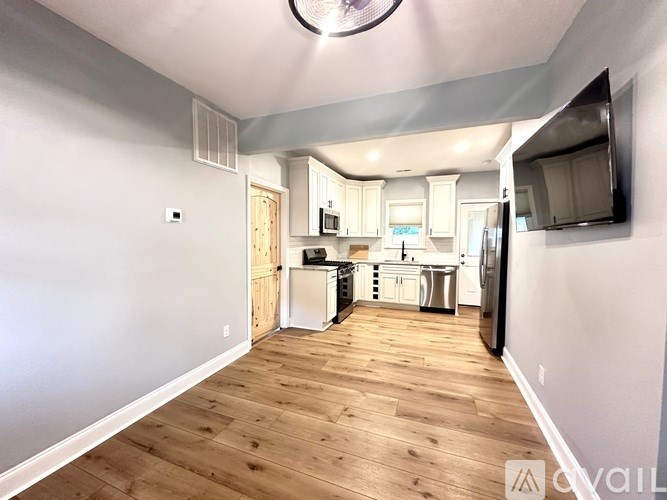 A kitchen with white cabinets and a wooden floor.