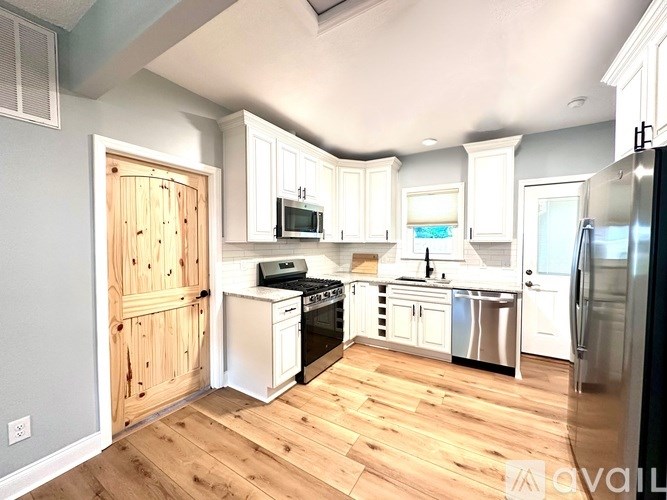 A kitchen with wooden floors and white cabinets.