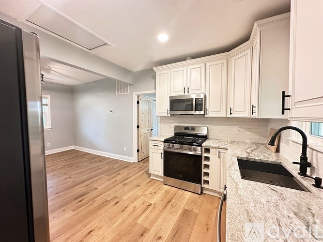 A kitchen with wooden floors and white cabinets.