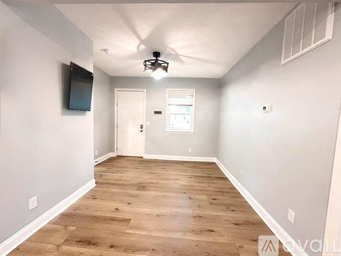 A spacious room with wooden flooring and a ceiling fan.