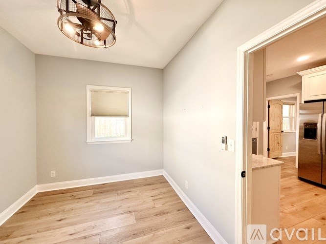 A room with a light grey wall and a window with white blinds.