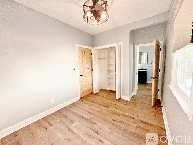 A room with wooden floors and a chandelier hanging from the ceiling.