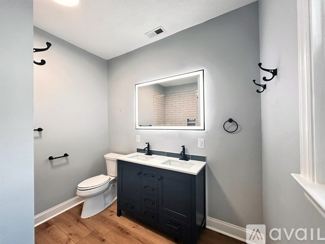 A bathroom with a white toilet, a sink with a black cabinet, and a mirror above the sink.