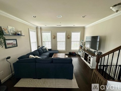 A living room with a dark blue couch and a striped rug.