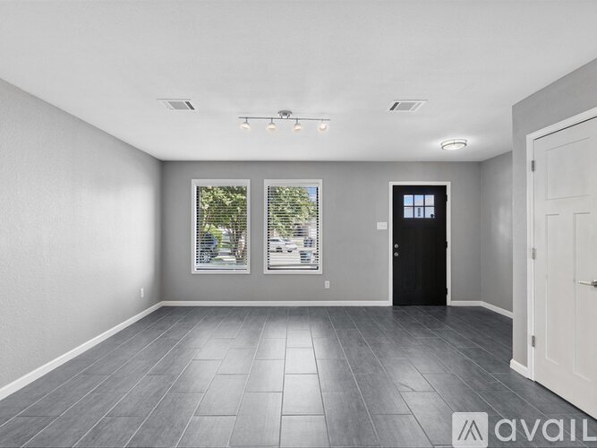 A spacious room with grey flooring and a black door.