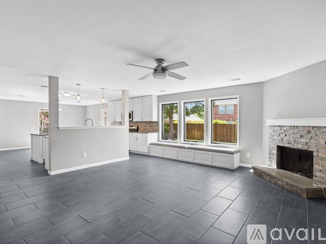 A spacious living room with a fireplace and a ceiling fan.