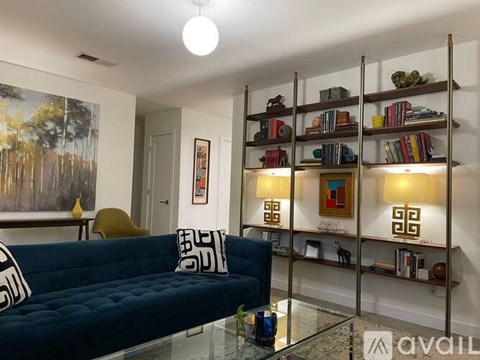 A living room with a blue couch and a bookshelf with books and decorative items.