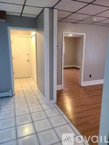A hallway with a tiled floor and two open doors.