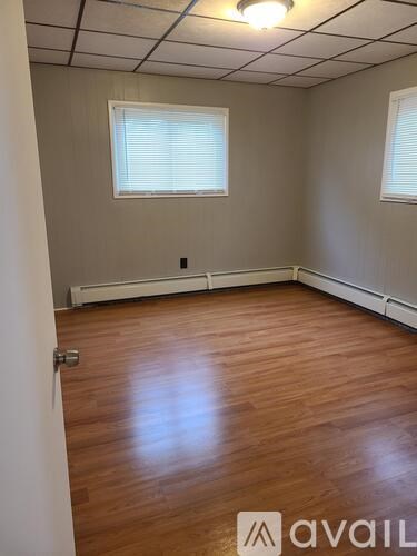 A room with wooden flooring and a window with blinds.