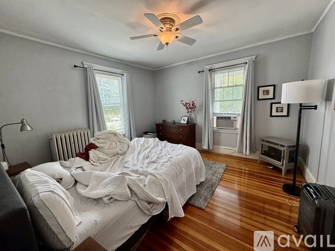 A bedroom with a bed in the center and a ceiling fan above it.