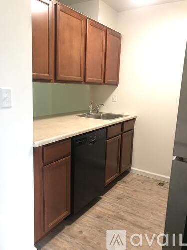 A kitchen with wooden cabinets and a black dishwasher.