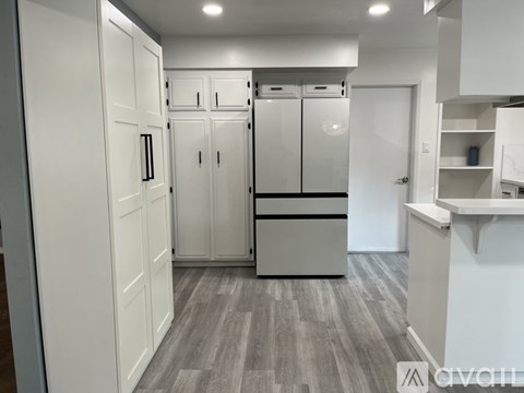A kitchen with white cabinets and a grey floor.