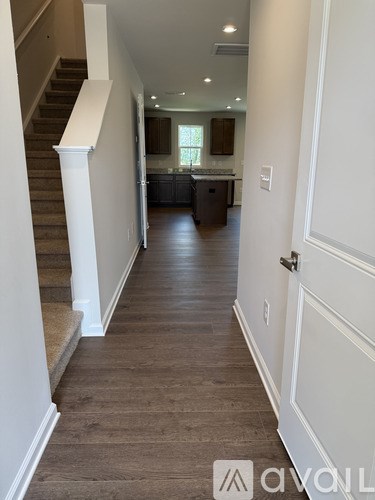 A hallway with a staircase on the left and a kitchen area on the right.