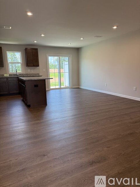 A spacious room with wooden flooring and a kitchen area with a sink and cabinets.