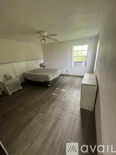 A bedroom with a bed, dresser, and window.