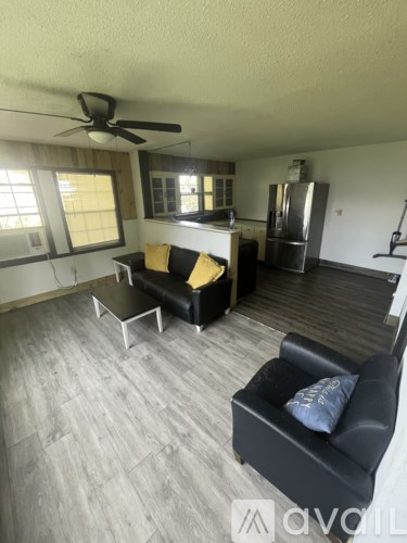 A living room with a black couch and a fan.