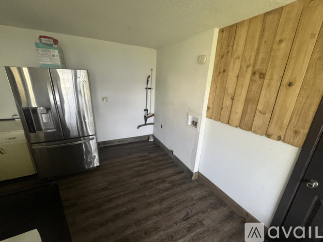 A kitchen with a refrigerator and a wooden wall.
