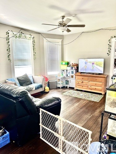 A living room with a black leather chair, a white couch, a wooden dresser, and a television on a wooden stand.