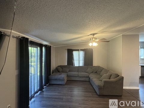 A living room with a grey couch and a fan on the ceiling.