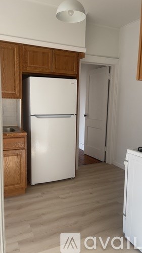 A white refrigerator in a kitchen with wooden cabinets.