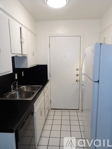 A kitchen with a sink, refrigerator, and cabinets.