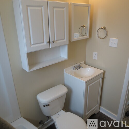 A small white bathroom with a toilet, sink and medicine cabinet.