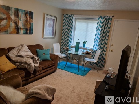A living room with a brown couch, a glass table, and a painting on the wall.