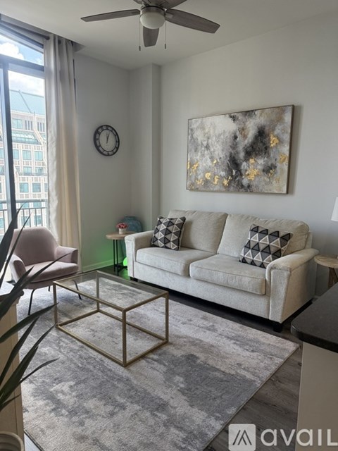 A living room with a white couch, a pink chair, and a large painting on the wall.
