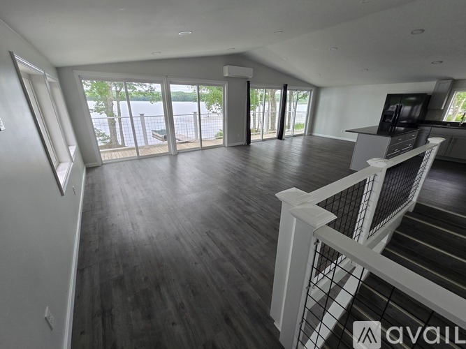 A spacious living room with a white railing and a view of the outdoors.