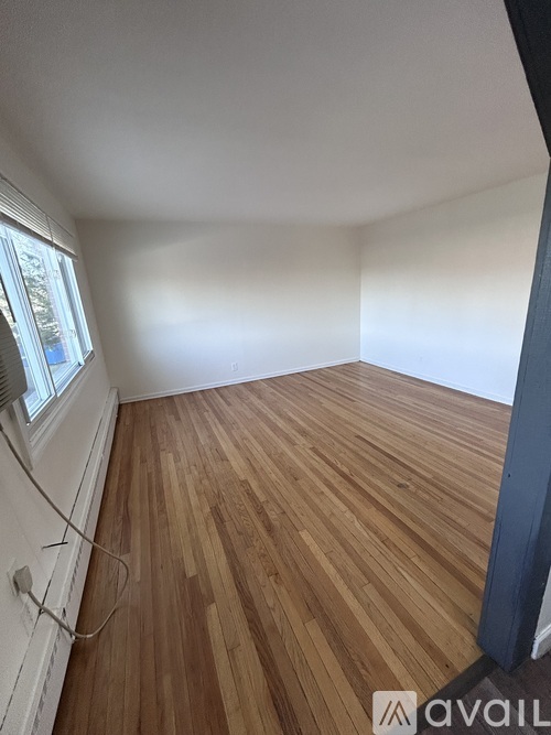 A room with wooden flooring and a window.
