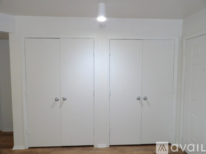Three white doors are closed in a room.