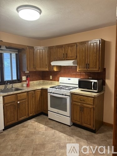 A kitchen with wooden cabinets and a white stove top oven.