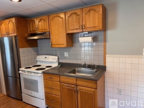 A kitchen with wooden cabinets and a white stove top oven.