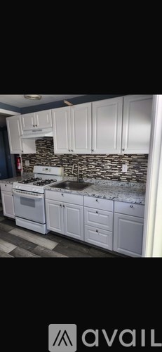 A kitchen with white cabinets and a stone backsplash.