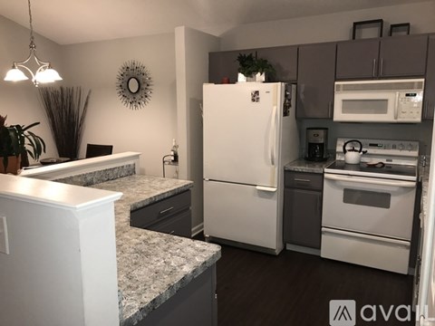 A kitchen with a white refrigerator and a white microwave above the stove.