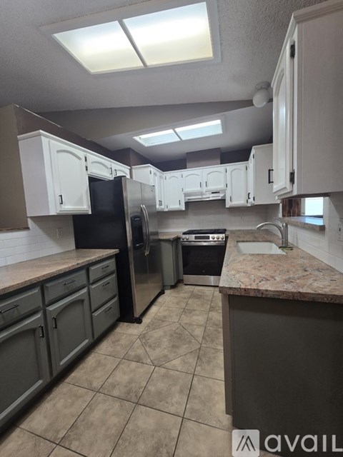 A kitchen with a black refrigerator and stainless steel appliances.