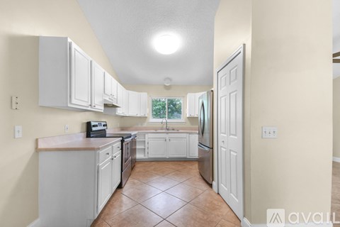 A kitchen with white cabinets and a tile floor.