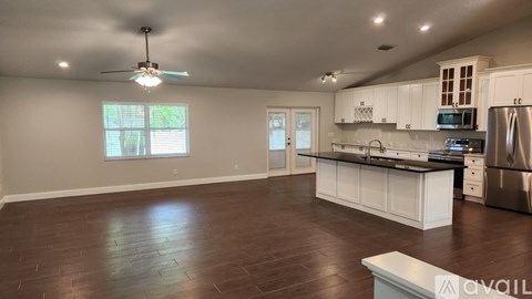 A spacious kitchen with white cabinets and a wooden floor.
