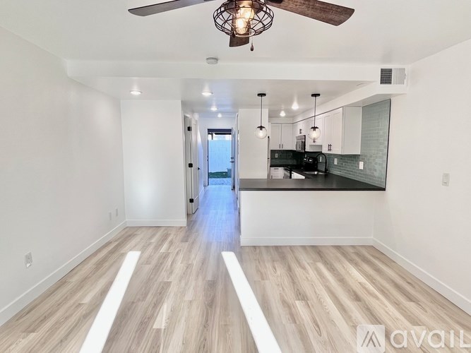 A spacious room with wooden flooring and a ceiling fan.