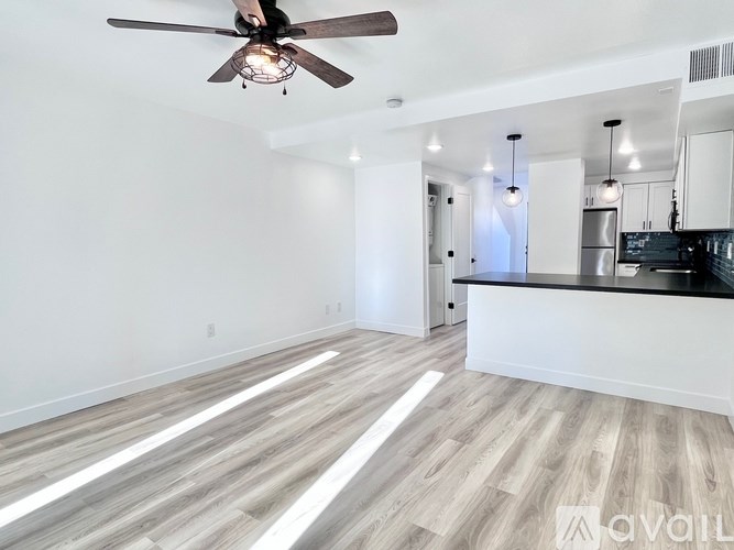 A spacious room with a ceiling fan and wooden flooring.