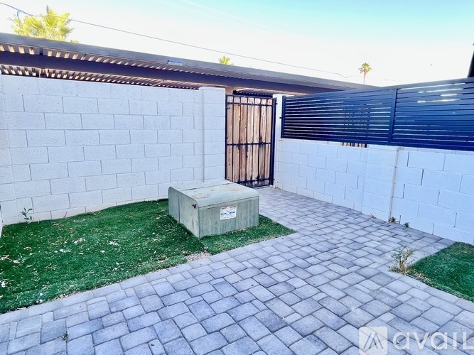 A backyard with a wooden gate and a brick patio.