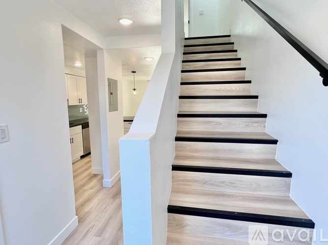 A staircase with wooden steps and a black handrail.
