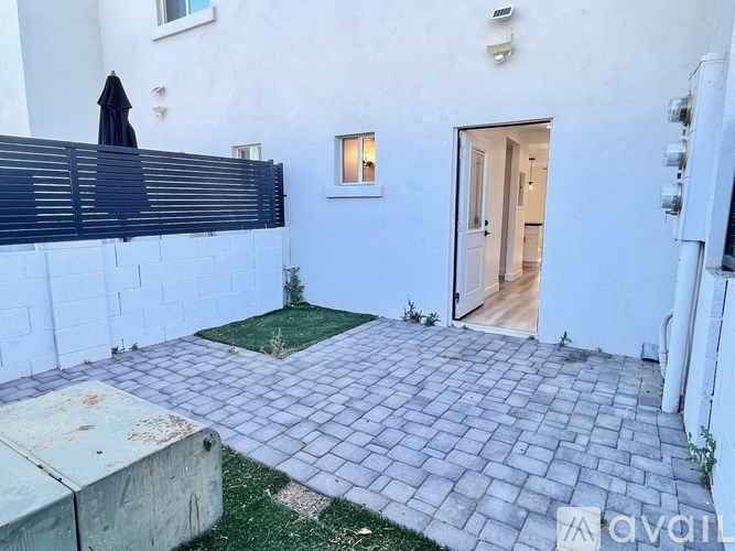 A patio with a black umbrella and a white wall.