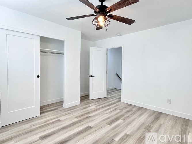 A room with a ceiling fan and light fixture, and a wooden floor.