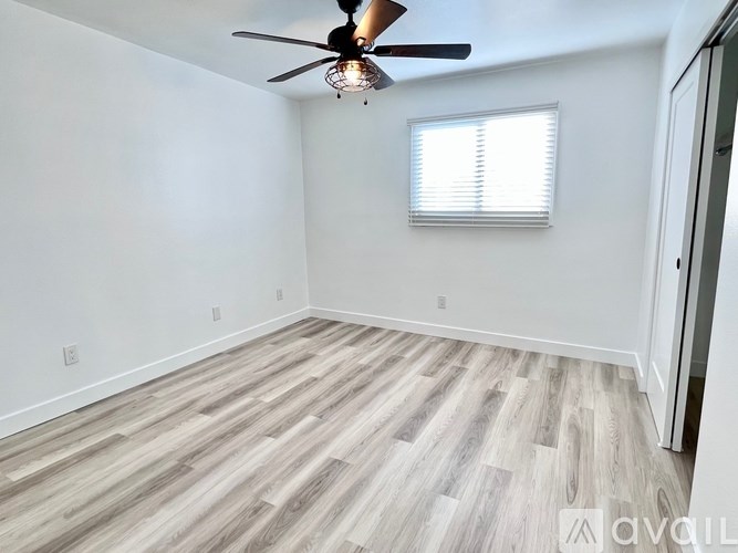 A room with a ceiling fan and a window with blinds.