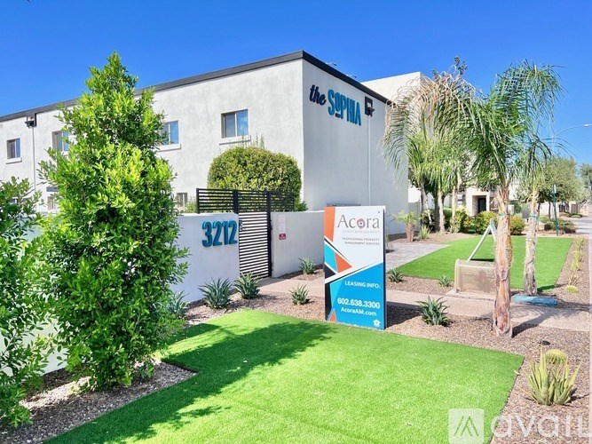 A well-maintained lawn in front of a building with a sign for Acerca 3272.